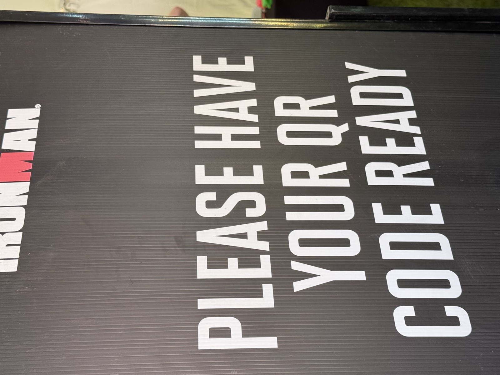 A signboard at athlete check-in reading “PLEASE HAVE YOUR QR CODE READY”